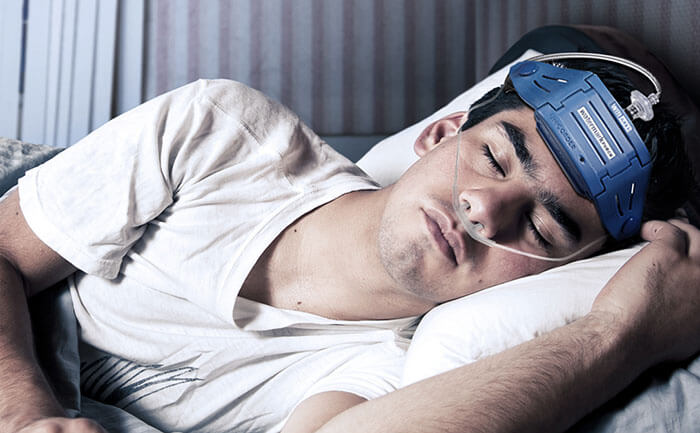 Sleeping man laying in bed, wearing a sleep test deviceSleeping man laying in bed, wearing a sleep test device